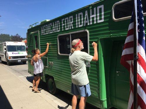 Supporters of “Reclaim Idaho”, the campaign supporting the expansion of Medicaid, sign their names on the infamous green Medicaid bus.