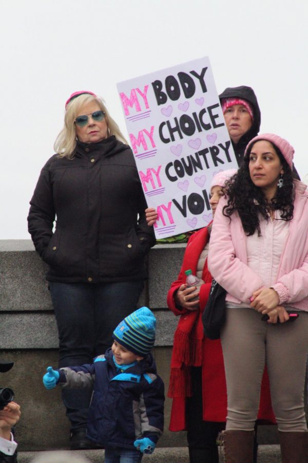 Women’s March participants gather near the speaker podium; facing the large crowd that makes up the Women’s March.  