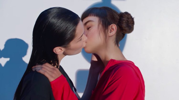 Bella Hadid, a heterosexual identifying woman, kissing a female-presenting robot, for an advertisement, which was later determined as queerbaiting by the general public since Hadid is not LGBTQ+. (Pride.com)