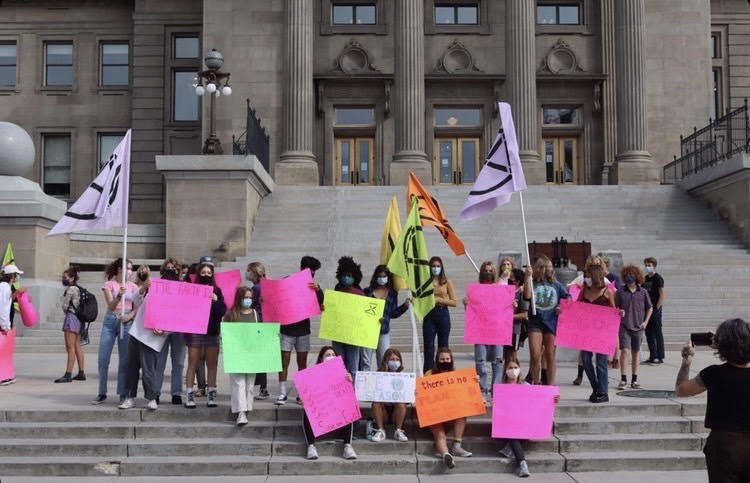 A gathering of students holding neon-colored signs and striking on the front steps of the Idaho Capitol Building to raise awareness about climate change as a part of a larger, worldwide movement.